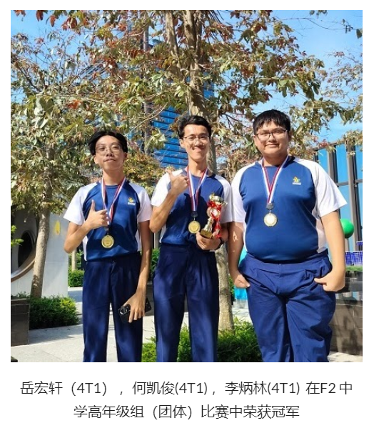 Three boys in blue uniforms wear gold medals outdoors, with the middle boy holding a trophy.